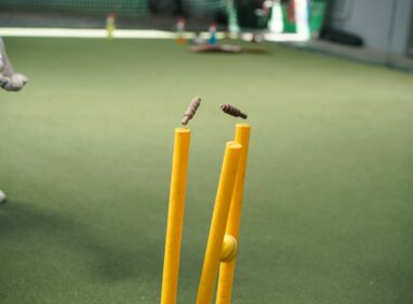 A man standing next to a yellow bat and ball