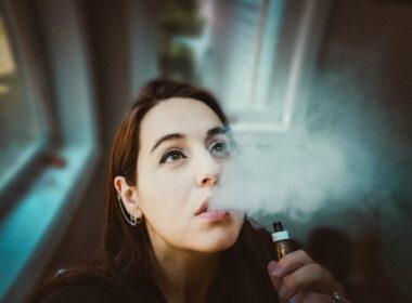 woman holding black and gold tube type vape