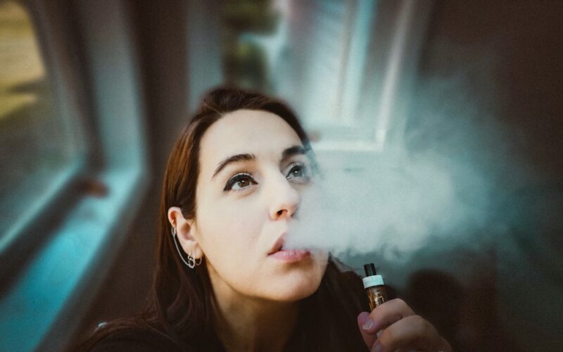 woman holding black and gold tube type vape
