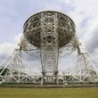 a large metal structure sitting on top of a lush green field