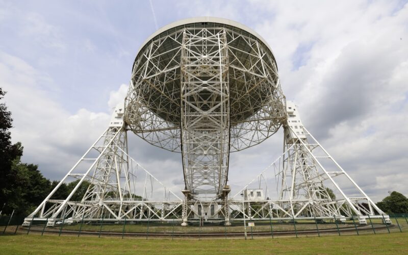 a large metal structure sitting on top of a lush green field