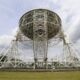 a large metal structure sitting on top of a lush green field