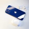 a blue iphone sitting next to a pair of ear buds