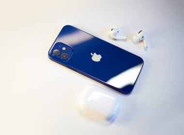 a blue iphone sitting next to a pair of ear buds