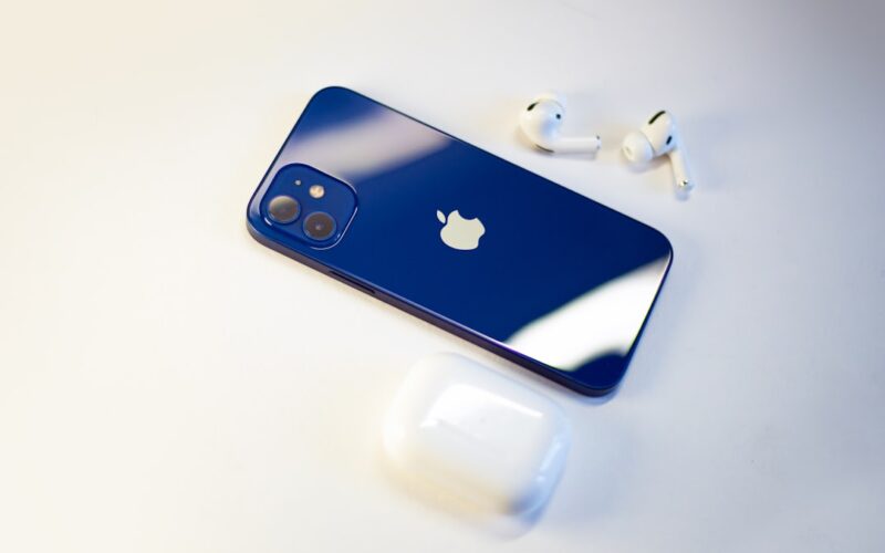 a blue iphone sitting next to a pair of ear buds