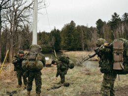 a group of soldiers walking across a grass covered field