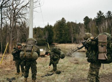 a group of soldiers walking across a grass covered field