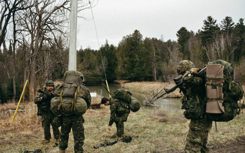 a group of soldiers walking across a grass covered field