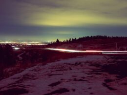 a snowy landscape with a road and trees in the background