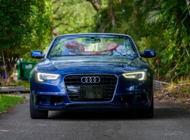 a blue car driving down a road next to trees