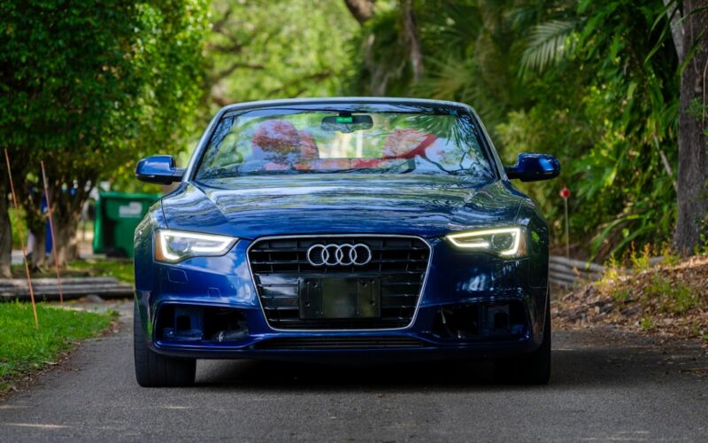 a blue car driving down a road next to trees