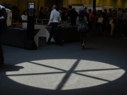 People walk near a spotlight on the floor.