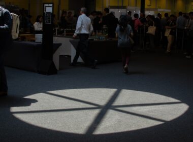 People walk near a spotlight on the floor.