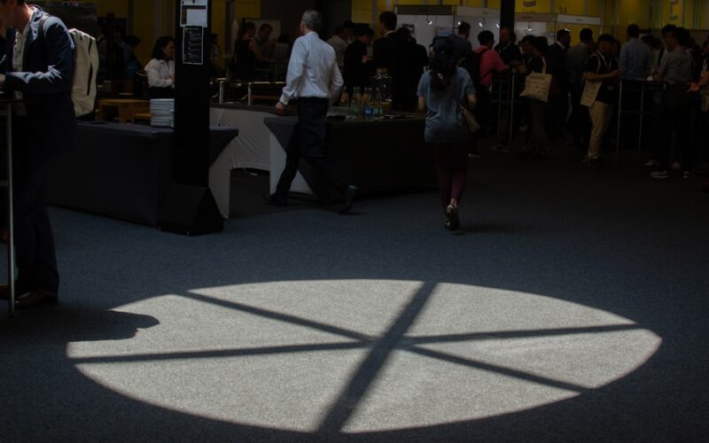 People walk near a spotlight on the floor.
