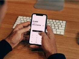 a man holding a cell phone in front of a keyboard