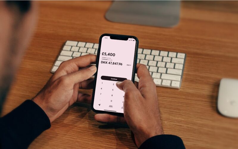 a man holding a cell phone in front of a keyboard
