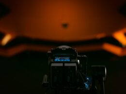 a close up of a camera with a helmet in the background