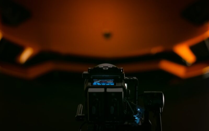 a close up of a camera with a helmet in the background