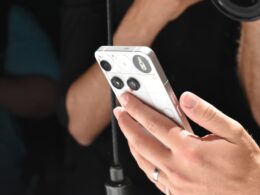 Person holding a white smartphone with a camera lens