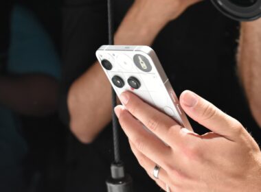 Person holding a white smartphone with a camera lens