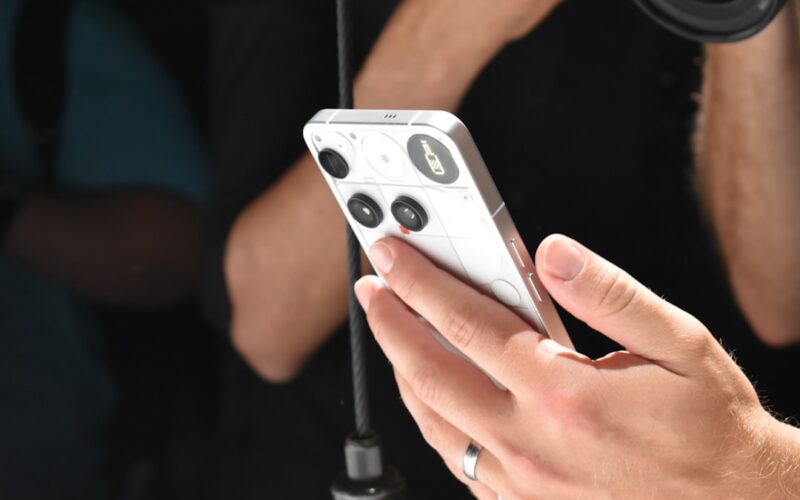 Person holding a white smartphone with a camera lens