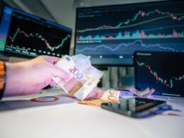 A person holding money in front of a computer screen