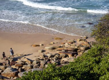 A couple of people standing on top of a sandy beach
