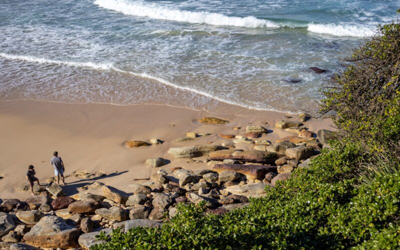A couple of people standing on top of a sandy beach