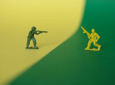 a toy soldier holding a gun next to a toy soldier