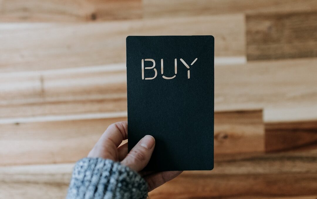 a person holding a black book with the word buy written on it