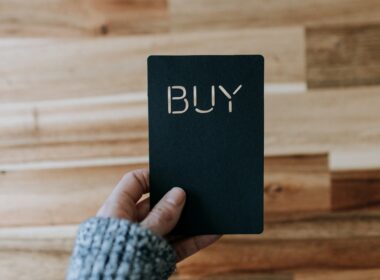 a person holding a black book with the word buy written on it