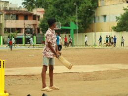 a man holding a bat standing next to a yellow post