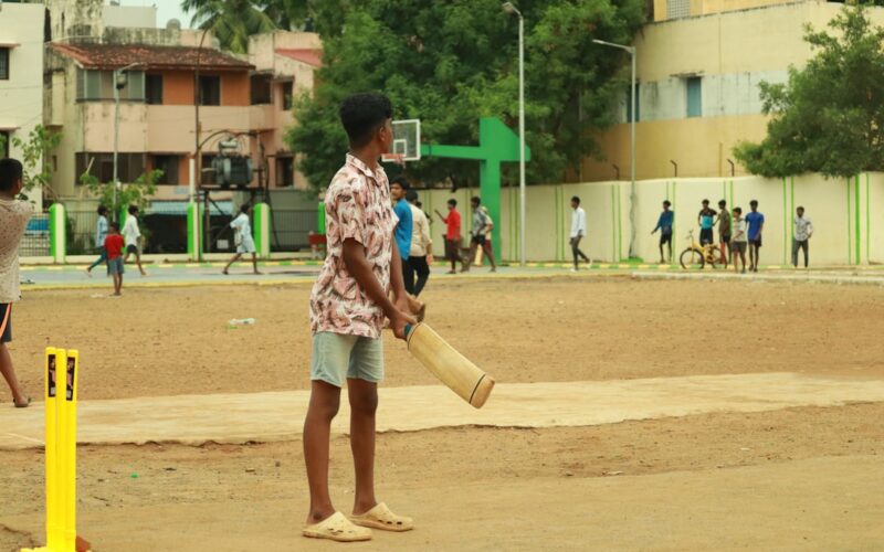 a man holding a bat standing next to a yellow post