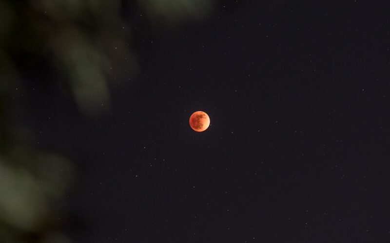 a red moon is seen in the night sky