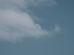 a plane flying in the sky with a half moon in the background