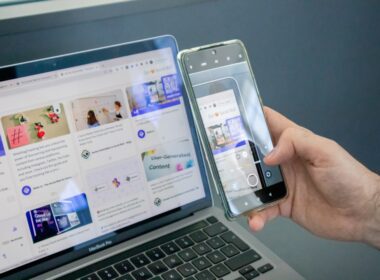 a person holding a cell phone next to a laptop