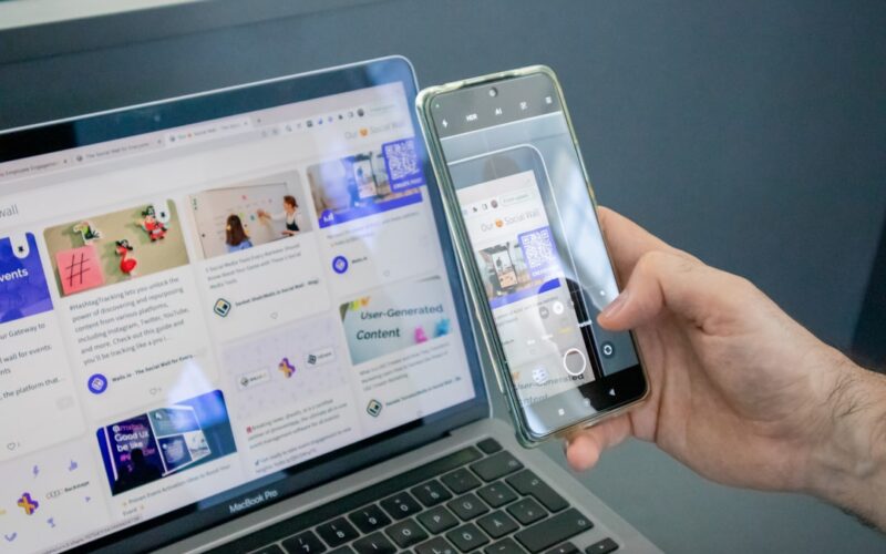 a person holding a cell phone next to a laptop