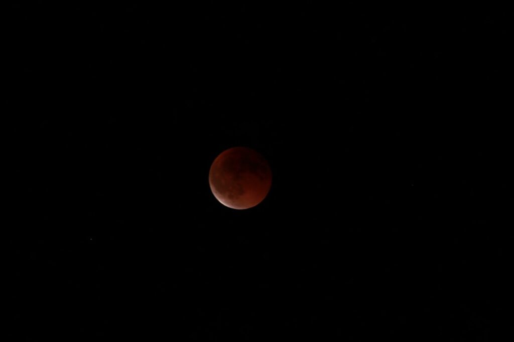 A blood moon illuminates the dark night sky.