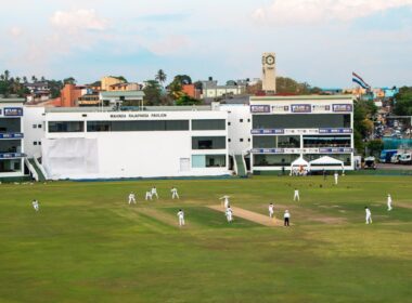 Cricket players are on a large green field.
