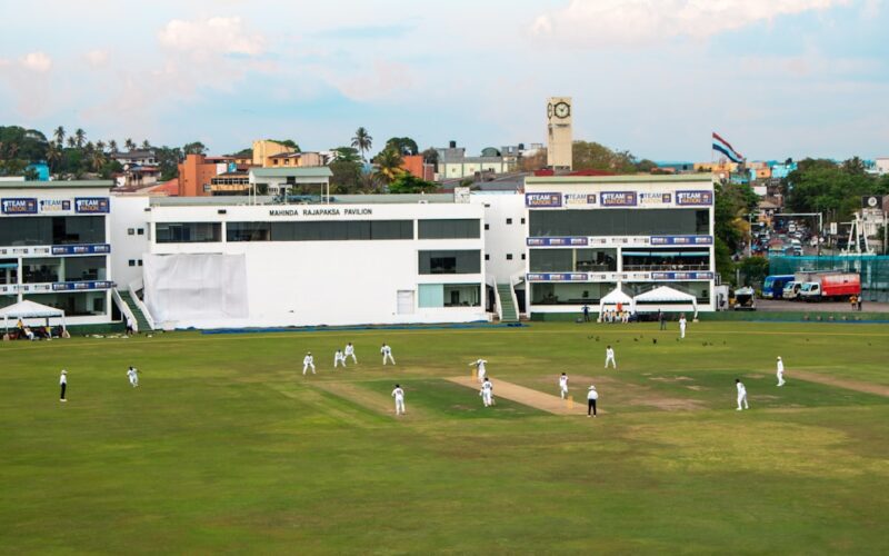 Cricket players are on a large green field.