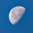 a half moon in a clear blue sky
