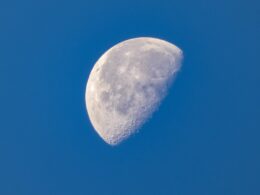 a half moon in a clear blue sky