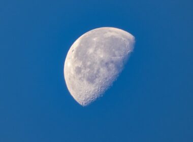 a half moon in a clear blue sky