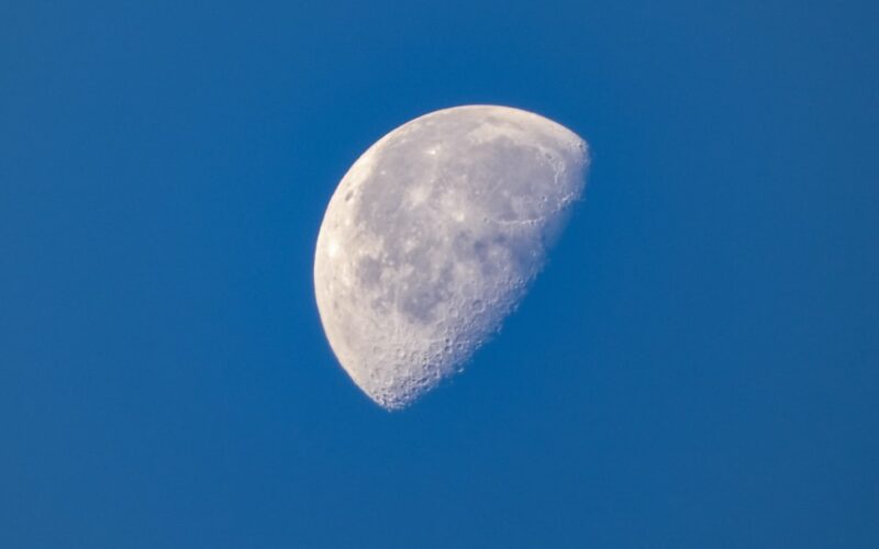 a half moon in a clear blue sky