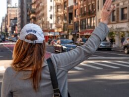 woman in gray long sleeve shirt and blue baseball cap standing on road during daytime