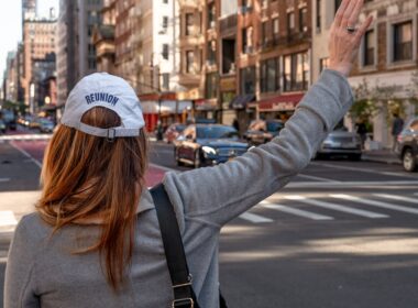 woman in gray long sleeve shirt and blue baseball cap standing on road during daytime