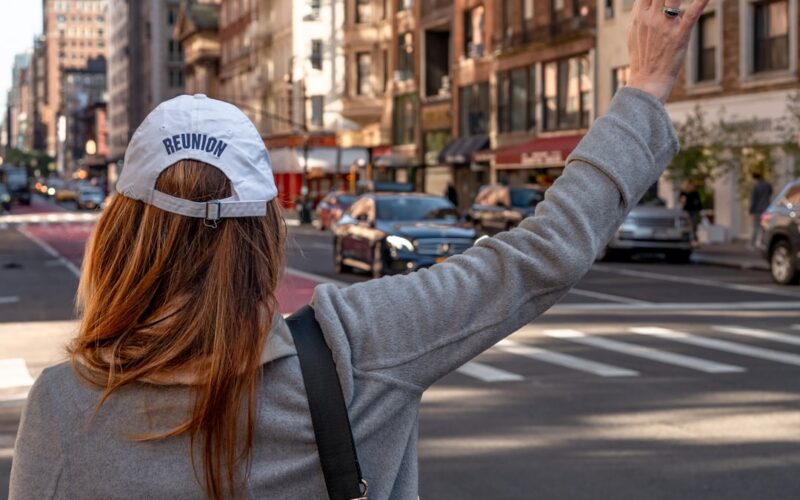 woman in gray long sleeve shirt and blue baseball cap standing on road during daytime