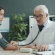 Doctor checks patient's blood pressure with stethoscope.