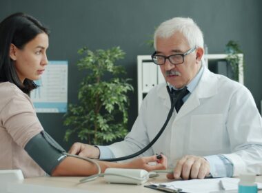 Doctor checks patient's blood pressure with stethoscope.