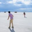 A couple of people that are standing in the sand